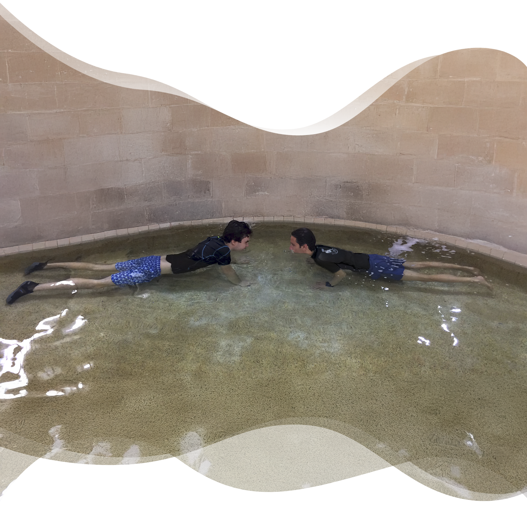 Student with autism practicing floating face down in shallow water, guided by Nereids swim teacher, building confidence through play.