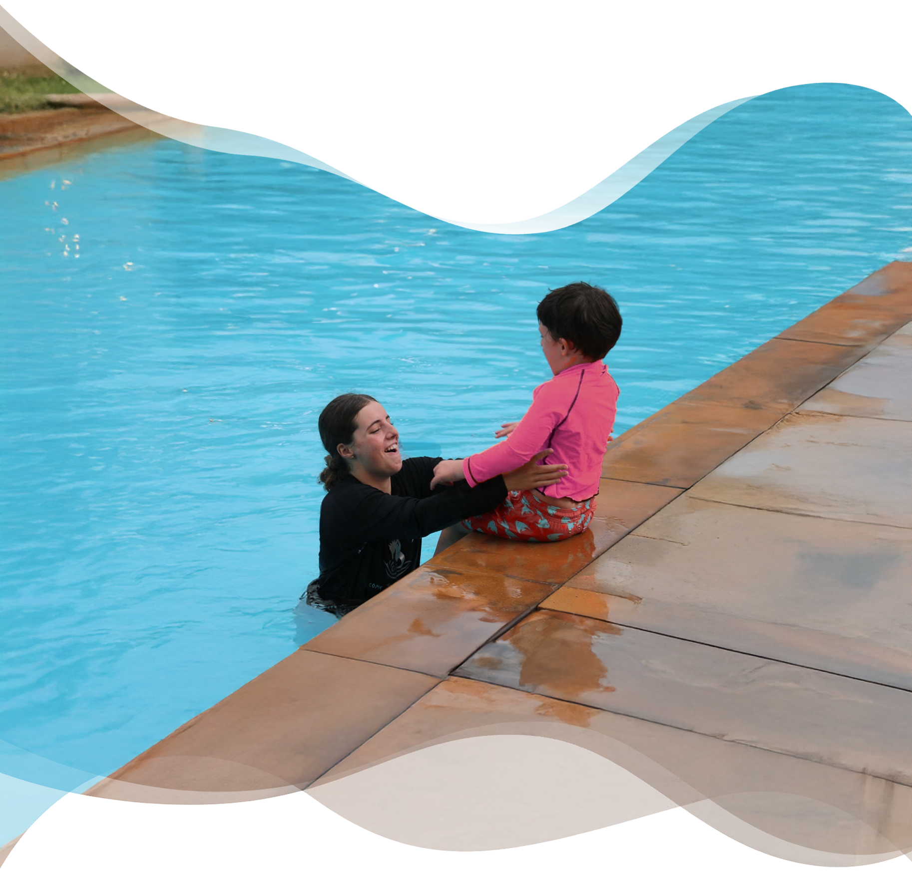 Nereids swim teacher laughing joyfully with a young student sitting on the pool edge, celebrating emotional connection and water confidence.
