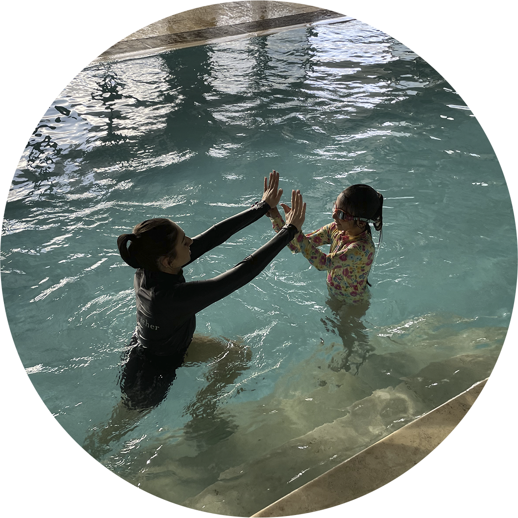 Nereids swim teacher and young student high-five in the pool after a private swimming lesson