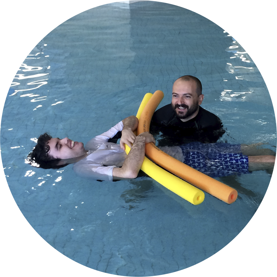 Swim teacher supporting an adult student with joy and care in the pool.