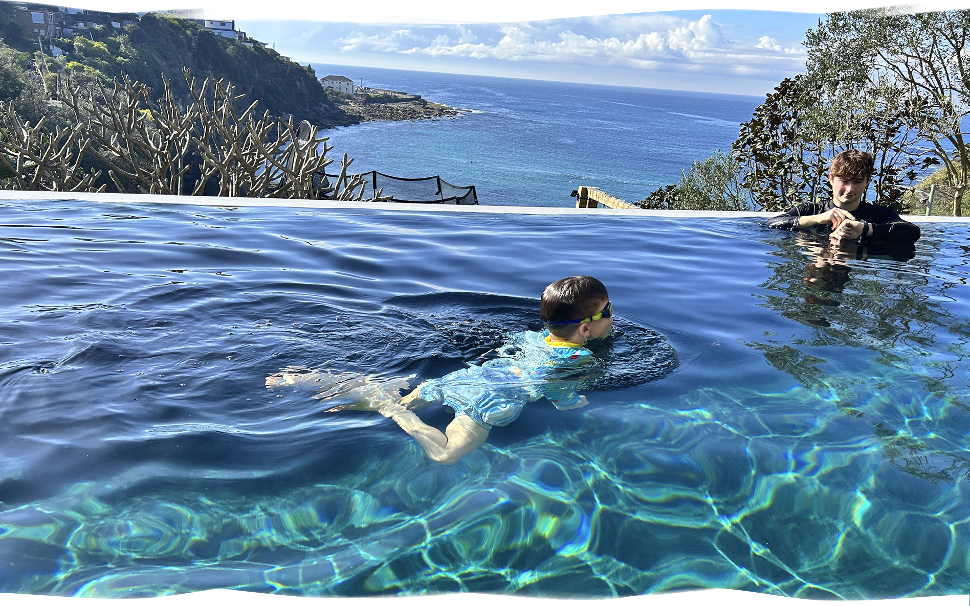 A confident child swims breaststroke across the pool while a Nereids swim teacher observes from a short distance, building independence and technique.