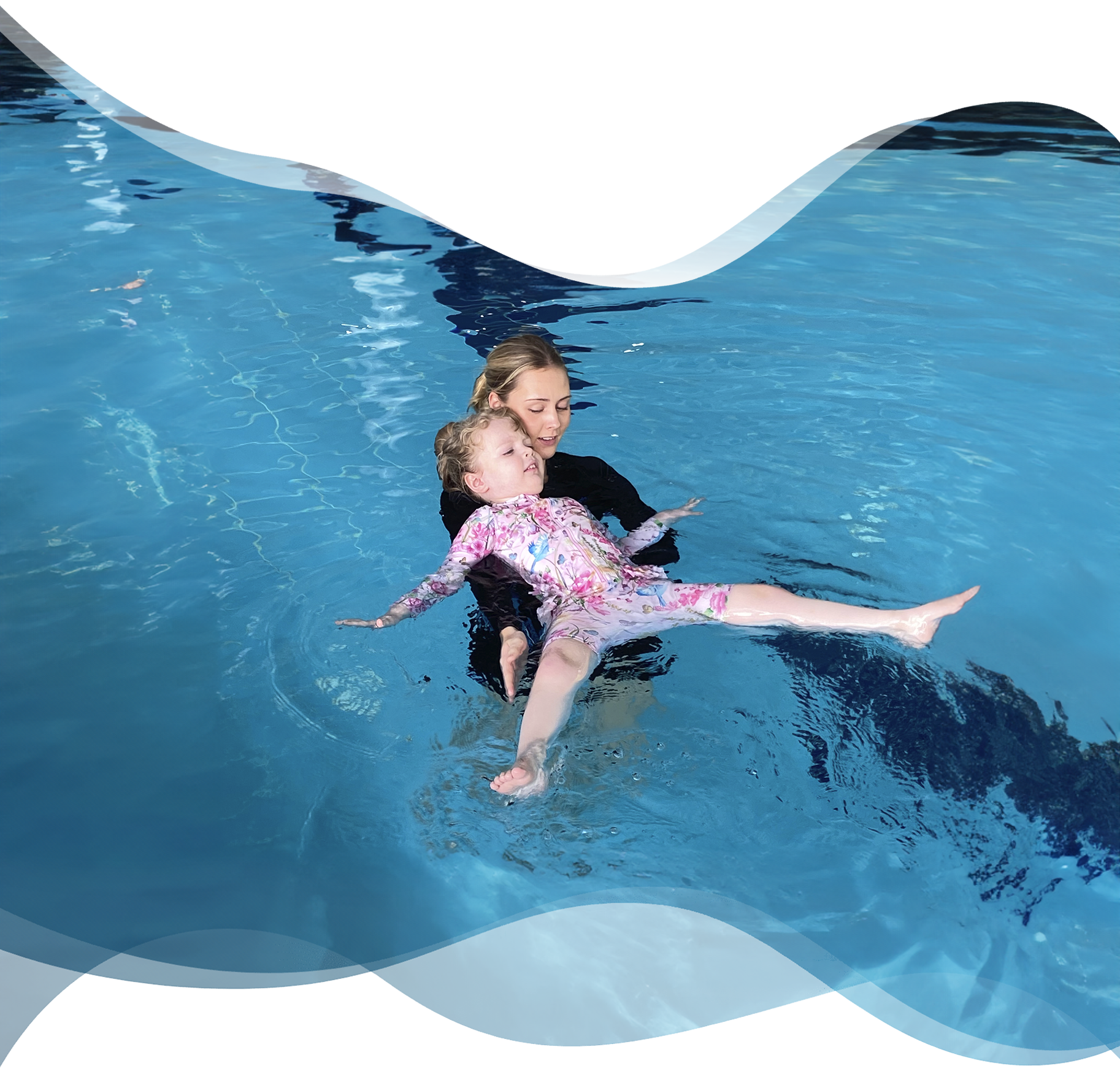 Nereids swim teacher gently supporting a nervous preschool girl keeping her head above water, showing care and patience during early fear-of-water moments.