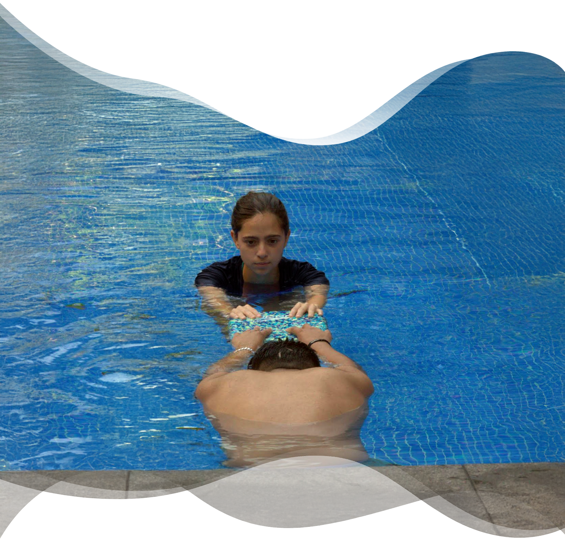 Adult holding kickboard in streamline position with submerged head as Nereids swim teacher prepares to guide the glide