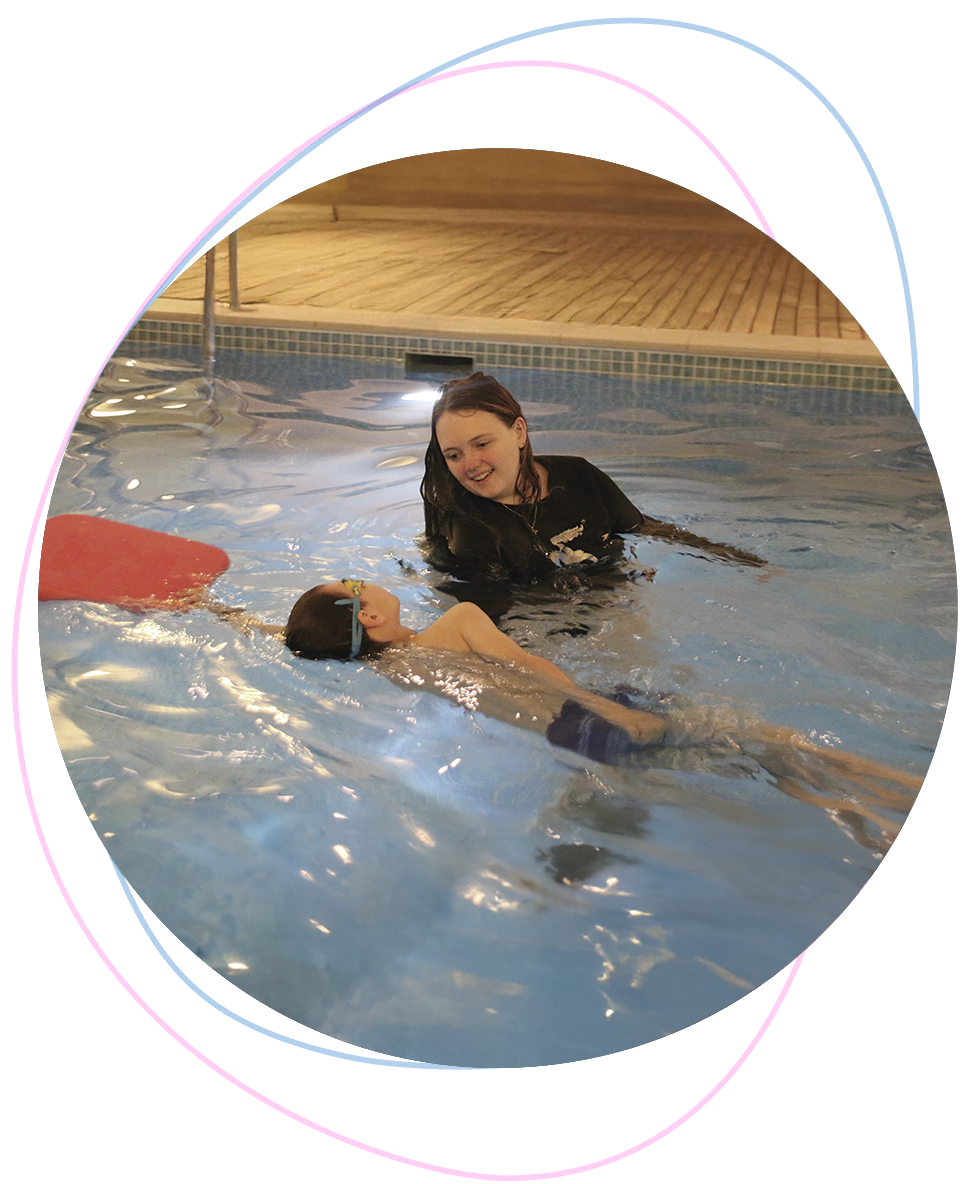 Young boy practices side breathing during freestyle as his Nereids swim teacher observes with care and focus, supporting technique and trust.