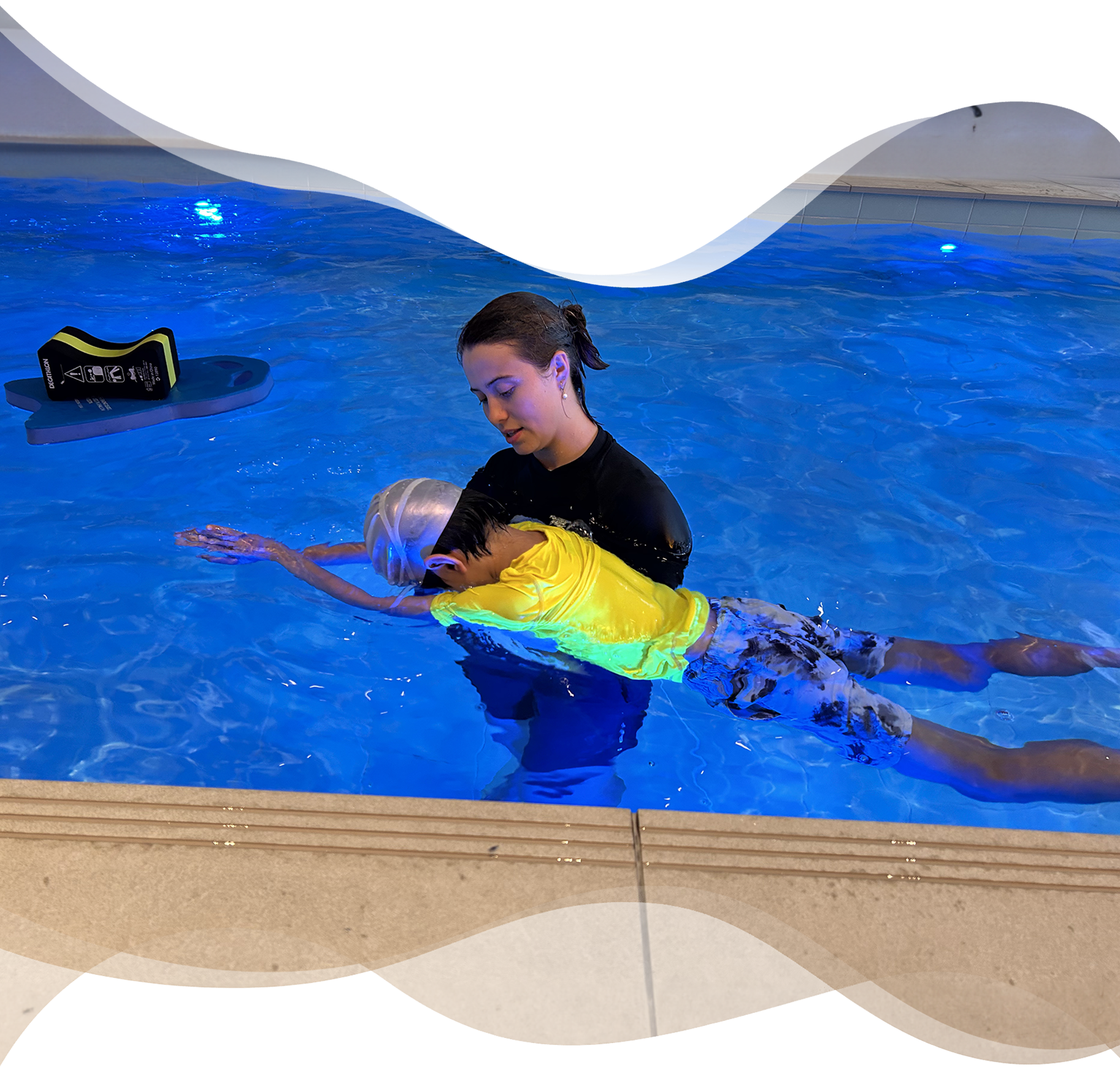 Nereids swim teacher supports a boy in a streamline position while he glides with his face underwater, emphasizing technique and gentle correction.
