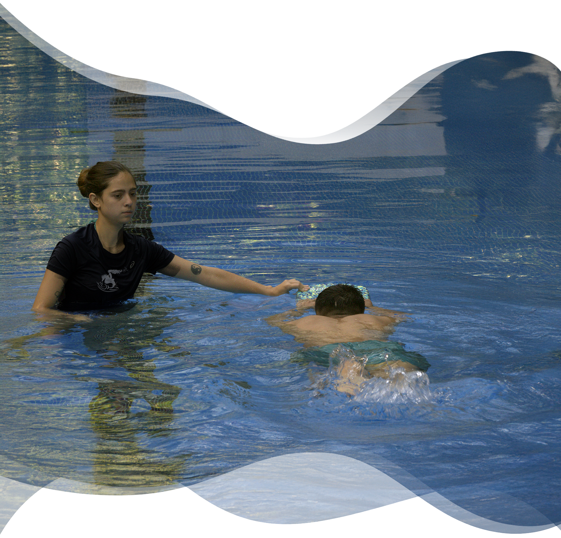 Adult swimmer practicing kickboard drill with head submerged as Nereids teacher gently adjusts technique