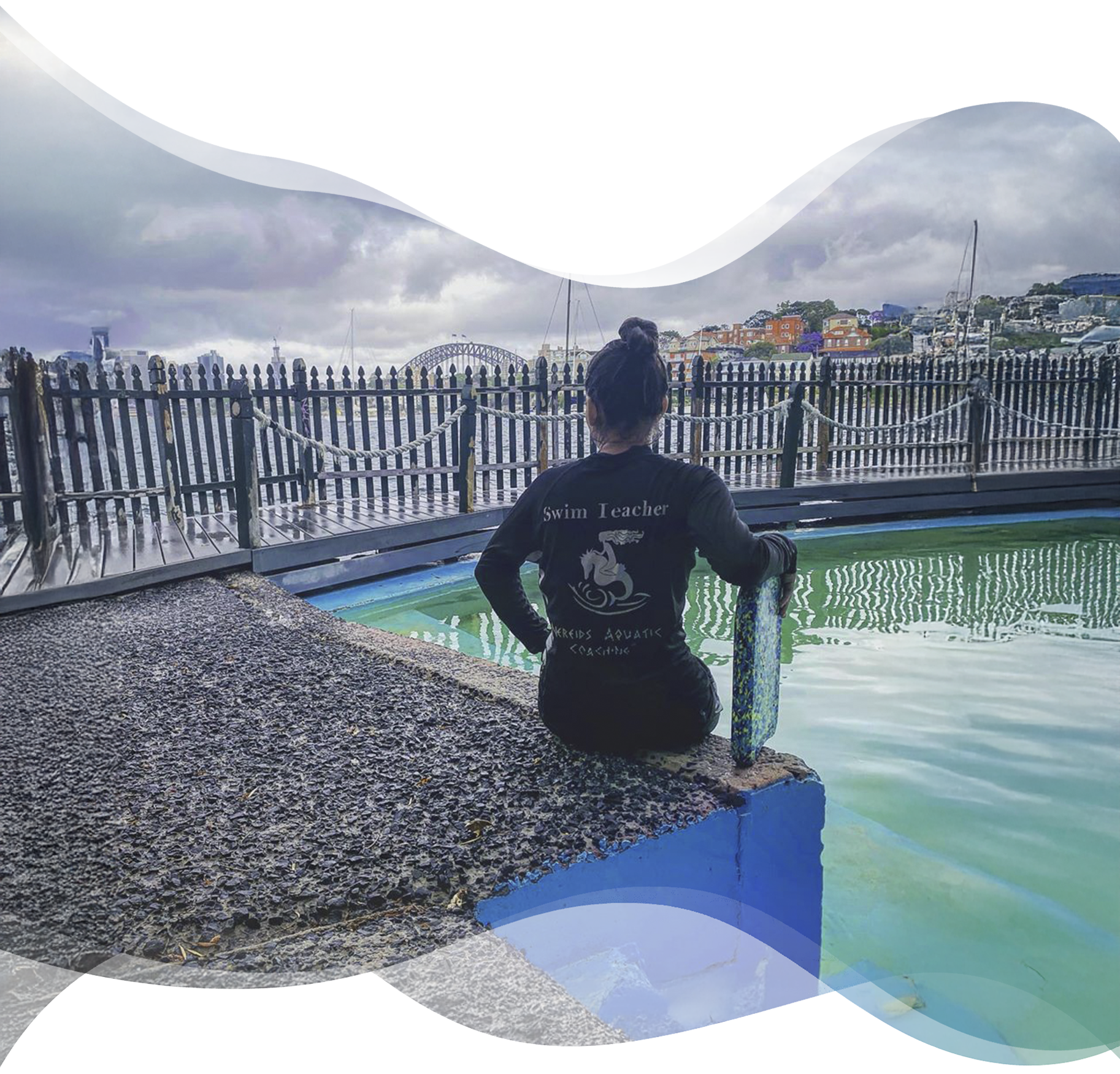 Nereids teacher sitting at edge of ocean rock pool looking at Sydney Harbour