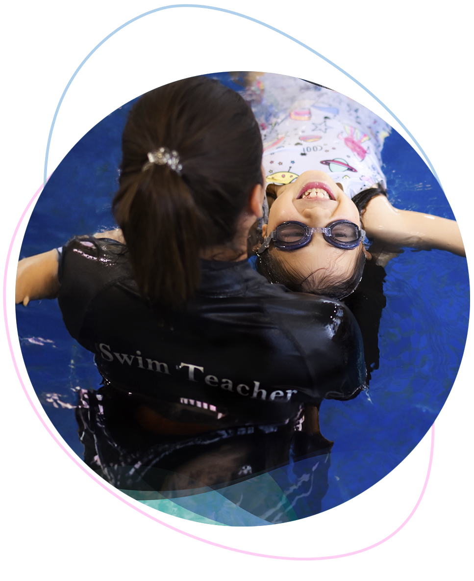 Happy young girl confidently floating in a starfish position while being gently supported by a Nereids swim teacher during a private water safety session.