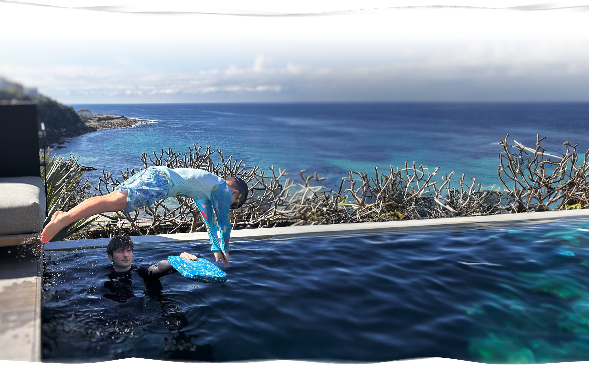 Confident young boy diving into the deep end while a Nereids swim teacher stays nearby for safety and guidance during a private swimming lesson.