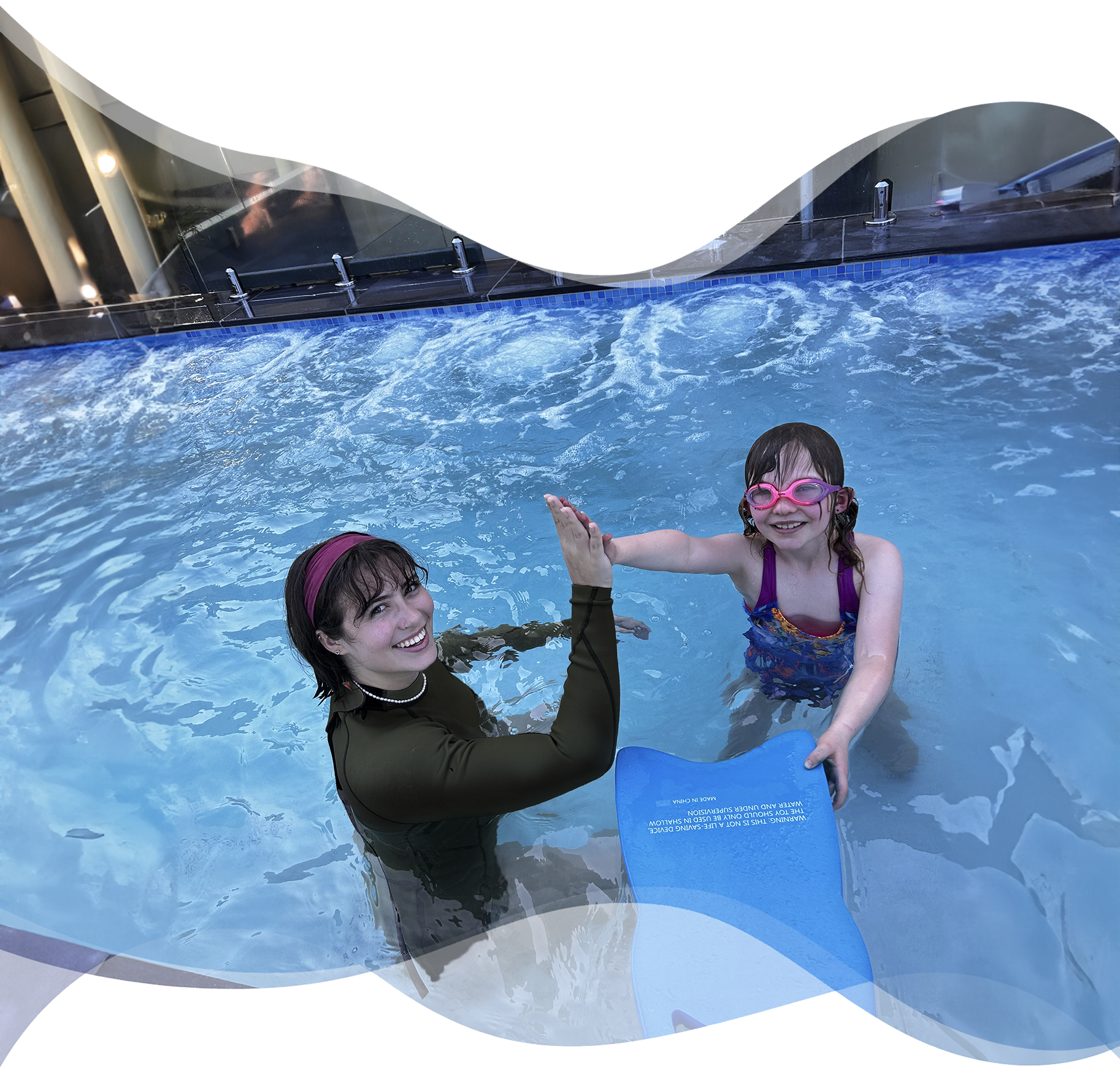 Nereids swim teacher high-fives a smiling student after a successful swim lesson, celebrating progress and water safety milestones.